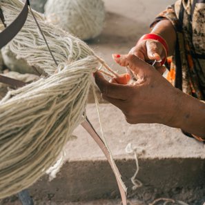 Hands separating the strands of a hank of cream yarn