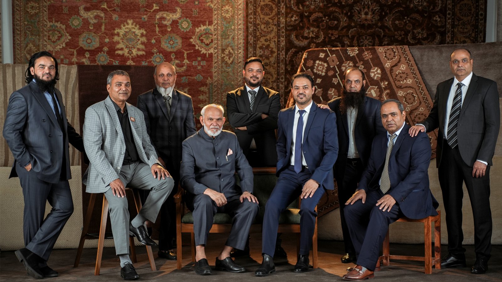 The RMC Collections team photographed together in front of hanging carpets