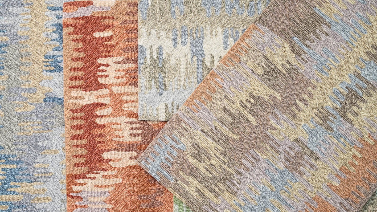 Two broadloom carpets with abstract patterns in terracotta, blue and gold laid side by side