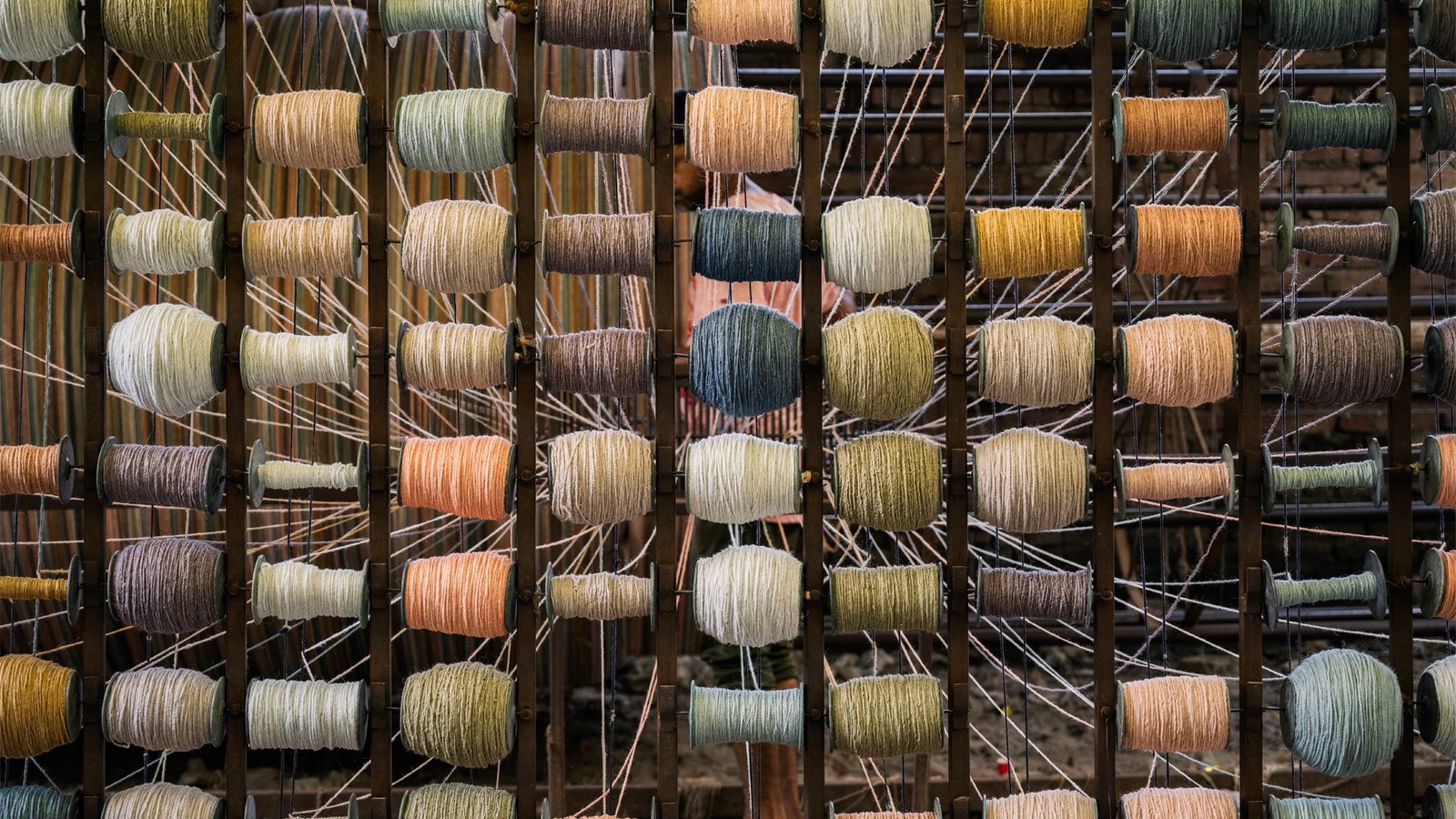 A rack of yarn bobbins in many colours arranged in rows