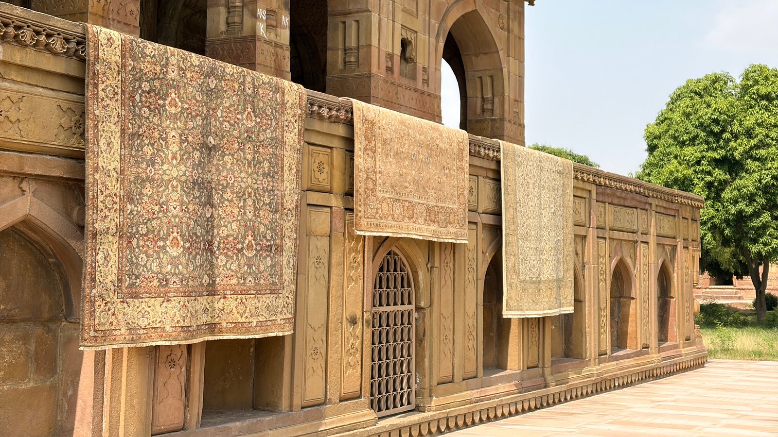 Carpets hung out to air along the arches of an old sandstone building