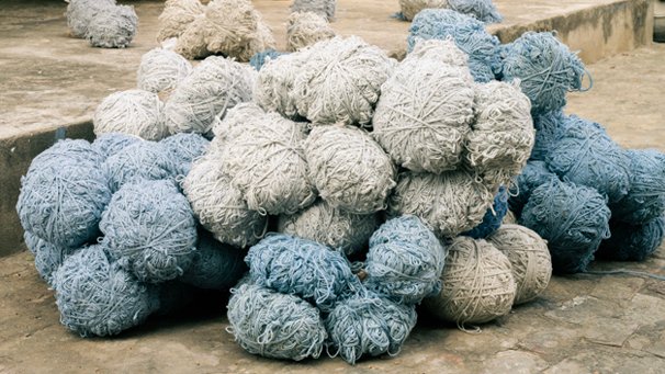 A pile of hand-dyed wool skeins in blue and natural white drying outdoors