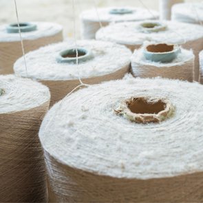 Large spools of undyed cream yarn stacked together